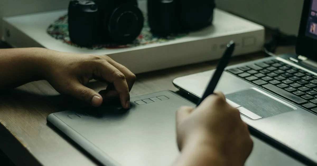 Persona editando una imagen en un portátil con tableta gráfica